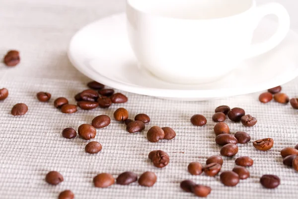 Coffee beans and white porcelain cup in the background — Stock Photo, Image