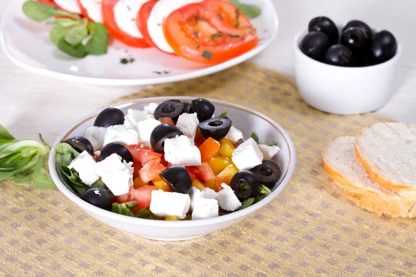 Греческий салат, хлеб и оливки на столе — стоковое фото