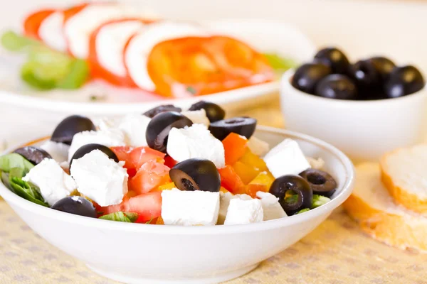 Греческий салат, хлеб и оливки на столе — стоковое фото