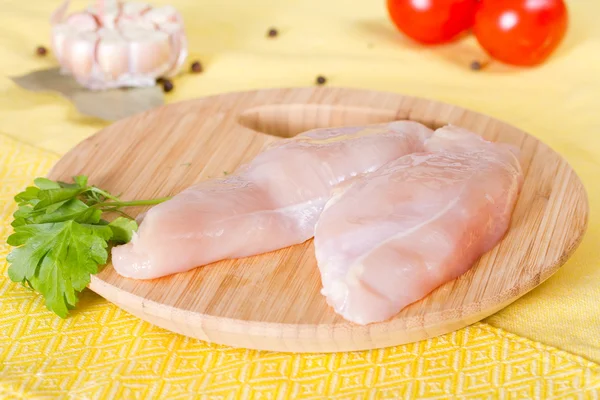 Filet de poulet et feuilles de persil sur une planche à découper — Photo