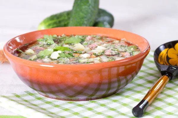 Okroshka em kvass em um boliche cerâmico em uma mesa e um spoo de madeira — Fotografia de Stock