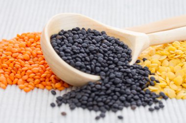 Tahta kaşık ile siyah, kırmızı ve sarı mercimek