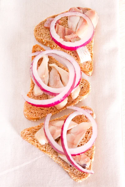 Сэндвич с ржаным хлебом, селедкой и красным луком — стоковое фото