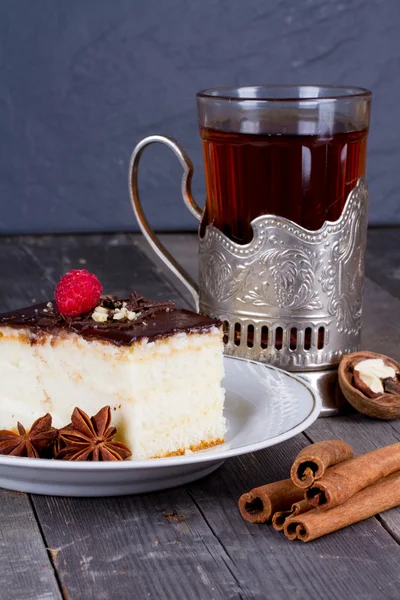 Bolo com creme de chocolate e uma xícara de chá no suporte da xícara de — Fotografia de Stock