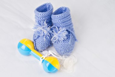 Rattle, pacifier and knitted booties for the newborn clipart