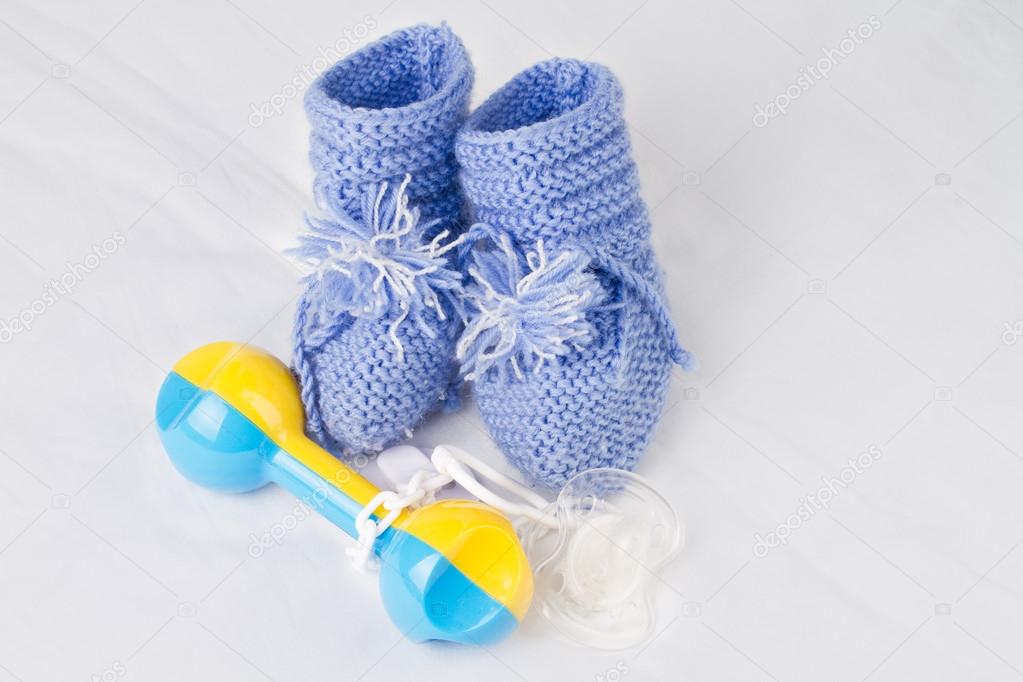 Rattle, pacifier and knitted booties for the newborn