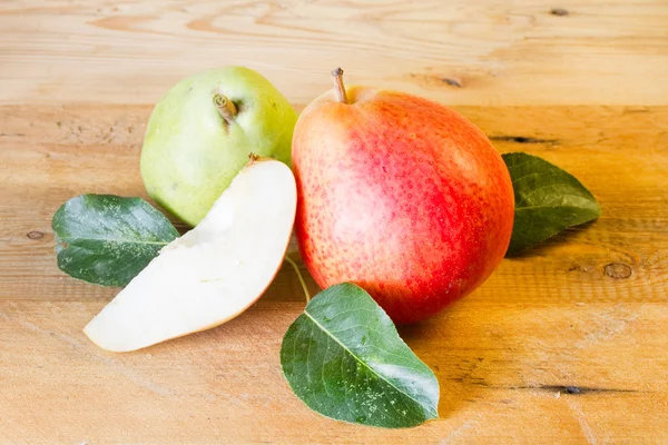 Whole and slice of ripe pears and green pear on a blackboard — Stock Photo, Image