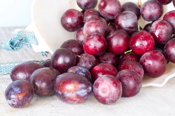 Ripe plums and cherry-plum on a white table