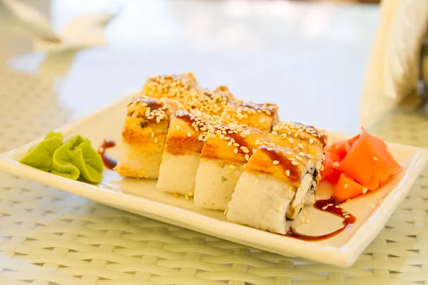Rolos com gengibre e wasabi em uma placa branca — Fotografia de Stock
