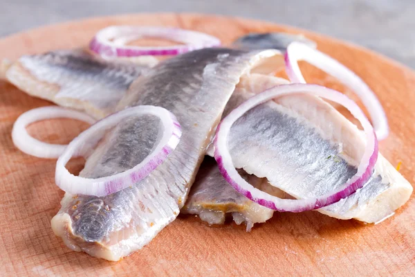 Trozos de filete de arenque en una tabla de cortar — Foto de Stock