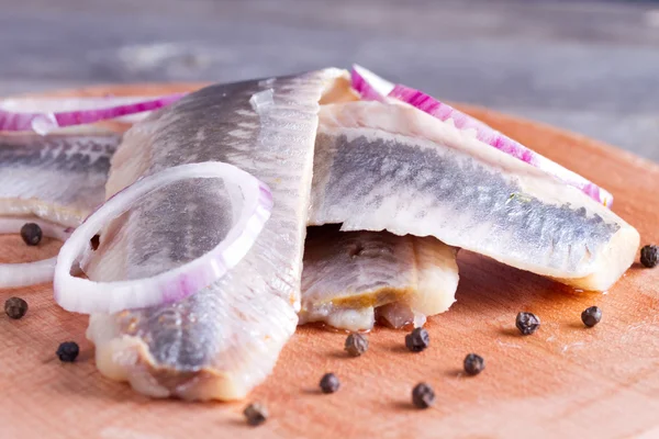 Trozos de filete de arenque en una tabla de cortar — Foto de Stock