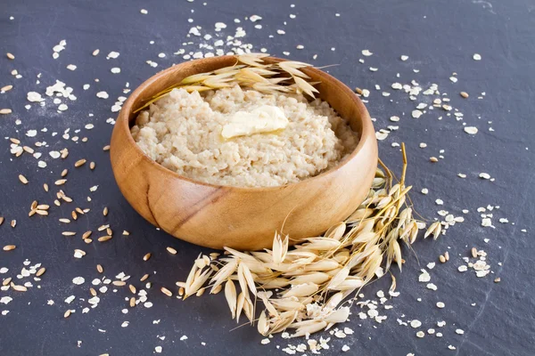 Oatmeal in a wooden bowl and ears of corn oat — Stock Photo, Image
