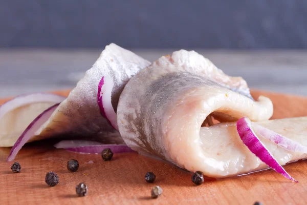 Pezzi di filetto di aringa su un tagliere Fotografia Stock