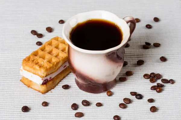 Šálek kávy, oplatky a kávová zrna na stůl — Stock fotografie
