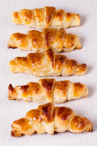 Croissant com uma crosta crocante em uma superfície branca — Fotografia de Stock