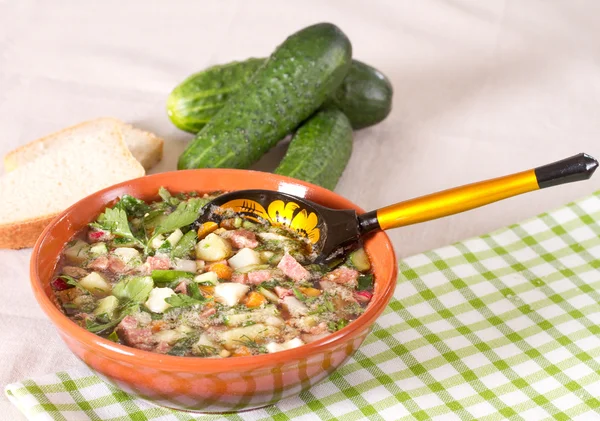 Okroshka on kvass in a ceramic bowl on a table and a wooden spoo — Stock Image Okroshka on kvass in a ceramic bowl on a table and a wooden spoo Stock Picture