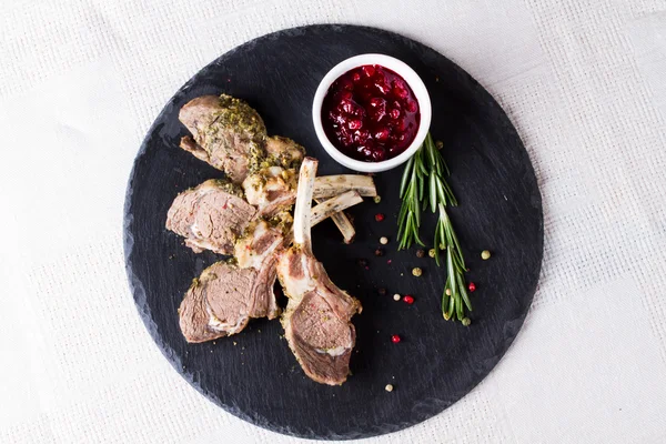 Bastidor de cordero con salsa de arándanos en una bandeja de piedra — Foto de Stock