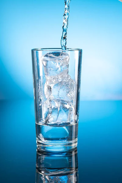 透明玻璃中的清澈冰水 在蓝色梯度背景上反射 — 图库照片