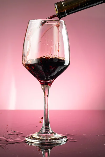 splash of red wine in glass on red background