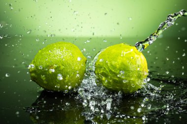 Arkaplanda iki yeşil limon ve su damlaları var.