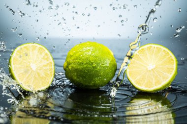 Arkaplanda iki yeşil limon ve su damlaları var.