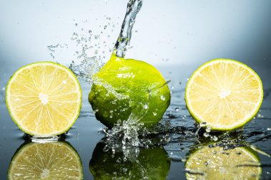 Arkaplanda iki yeşil limon ve su damlaları var.