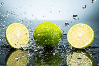 Arkaplanda iki yeşil limon ve su damlaları var.
