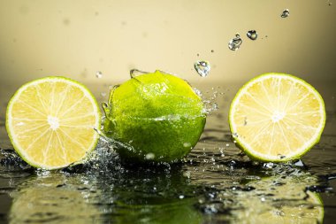 Arkaplanda iki yeşil limon ve su damlaları var.