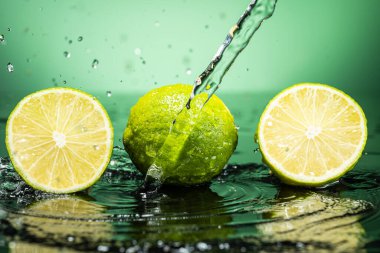 Arkaplanda iki yeşil limon ve su damlaları var.