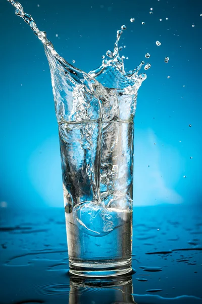 Stänk Ett Glas Vatten Från Fallande Isbit Blå Bakgrund — Stockfoto