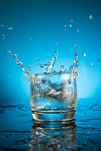 Розчавити Склянці Води Падаючого Шматка Льоду Синьому Фоні — стокове фото