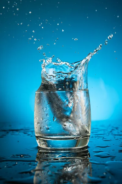 Espalhe Copo Água Pedaço Gelo Queda Fundo Azul — Fotografia de Stock