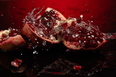 Beyaz tabakta tam nar meyvesi ve su sıçraması.