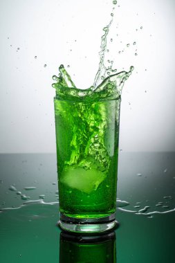 Açık arkaplanda yeşil tarhun limonatalı uzun şeffaf cam.