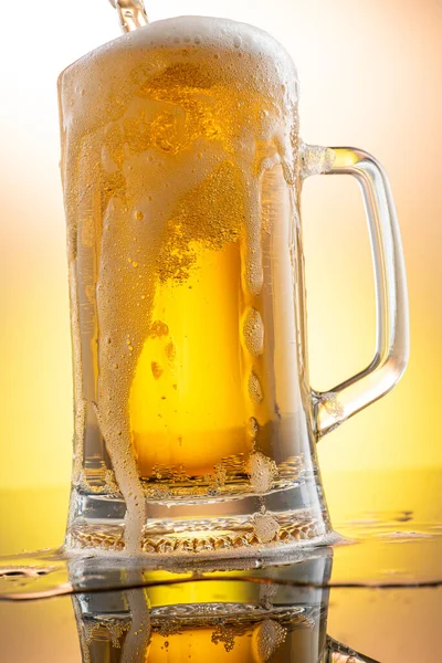 pouring beer into beer glass from bottle on yellow background