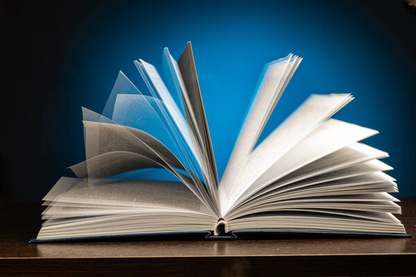 пролистывание страниц открытой книги на синем фоне