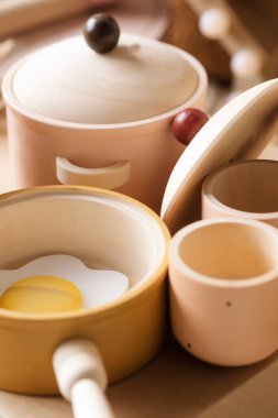 Pastel renklerde doğal ahşaptan yapılmış çocuk sofra takımı. Çocuk mutfağı oyunu, tencere, fincanlar, çırpılmış yumurtalı tava..