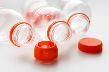 Geri dönüşüm için turuncu kapaklı plastik şişeler beyaz bir masada yatıyor. Plastik ve ekolojinin geri dönüşümü kavramı. Plastik atık. Doğa saçmalığını durdur
