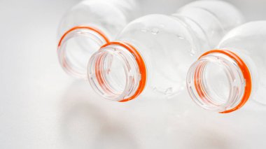 Geri dönüşüm için turuncu kapaklı plastik şişeler beyaz bir masada yatıyor. Plastik ve ekolojinin geri dönüşümü kavramı. Plastik atık. Doğa saçmalığını durdur