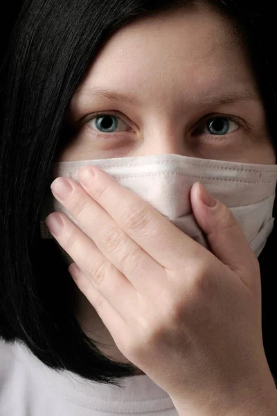 A young girl in a medical mask sneezes, covering her mouth with her hands. The concept of the seasonal infections, Flu, Rhinitis, cold, sickness, allergy, Coronavirus