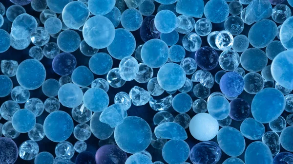 Close up - Pile of silica gel on blue background, Desiccant used in industrial, moisture protection. Desiccant Silica Gel (Moisture Absorber) Background. Blue and White Translucent Crystals Texture