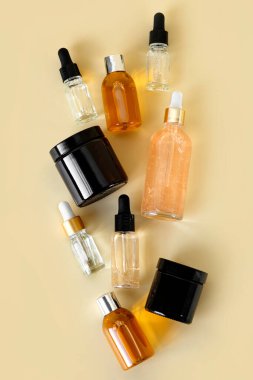 Kozmetik ürünleri için farklı cam şişeler, doğal ilaçlar, gerekli yağlar veya bej arka planda izole edilmiş diğer sıvılar. Kozmetik şişeleri taklit ediyor. Kimlik modelleme konsepti.