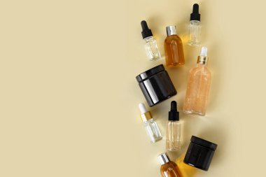 Kozmetik ürünleri için farklı cam şişeler, doğal ilaçlar, gerekli yağlar veya bej arka planda izole edilmiş diğer sıvılar. Kozmetik şişeleri taklit ediyor. Kimlik modelleme konsepti.