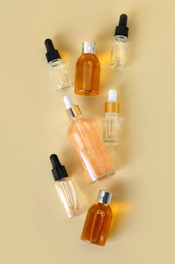 Kozmetik ürünleri için farklı cam şişeler, doğal ilaçlar, gerekli yağlar veya bej arka planda izole edilmiş diğer sıvılar. Kozmetik şişeleri taklit ediyor. Kimlik modelleme konsepti.