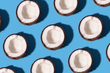 Taze hindistan cevizli desen, pastel mavi arka planda ikiye bölünmüş. Yarım hindistan cevizi, az düz stil, üst manzara. Yaz konsepti.