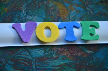 Ahşap arkaplanda renkli harflerle oy metni