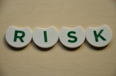 Tahta arka planda beyaz küplerle yazılmış riskli kelime