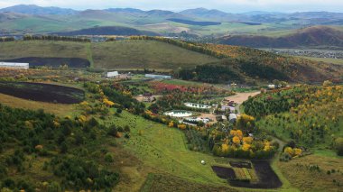 Sonbaharda Altai dağları. Altayskoye köyü. Visterra şirketinin üretim üssü. Dendropark. Altai Kholmogorye turistik bölgesi. Belokurikha tatil köyünün çevresi. Hava görünümü.