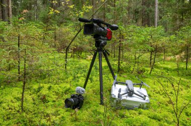 Yeşil yosun arka planında bir kamera, bir kamera ve bir helikopter. Video çekimi için bir takım ekipman..