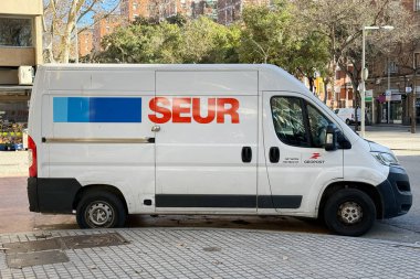 Beyaz SEUR teslimat minibüsü güneşli bir şehir sokağına park edilmiş, şirket logosu ve kargo kapısı kurye servisi, şehir lojistiği.